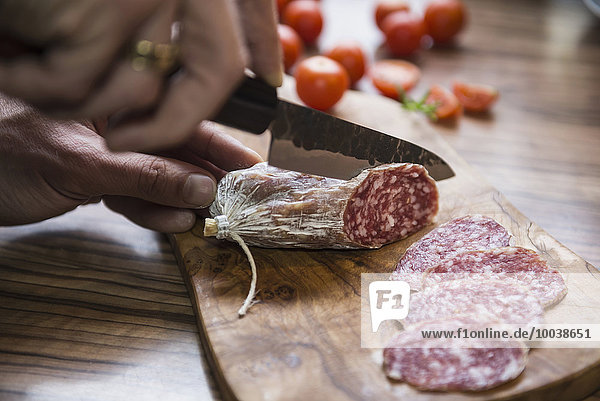 Person's hand chopping sausage with knife  Germany
