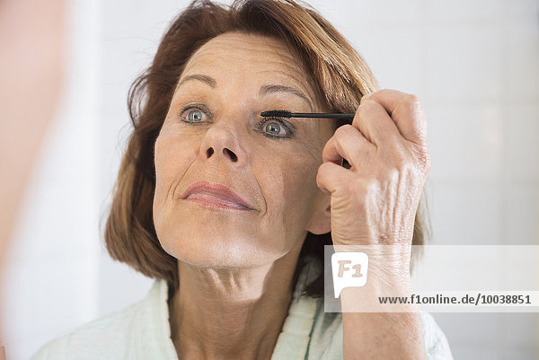 Senior woman applying eye make up with mascara  Munich  Bavaria  Germany