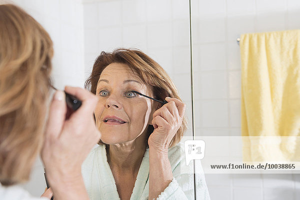 Reflection of a senior woman applying mascara  Munich  Bavaria  Germany