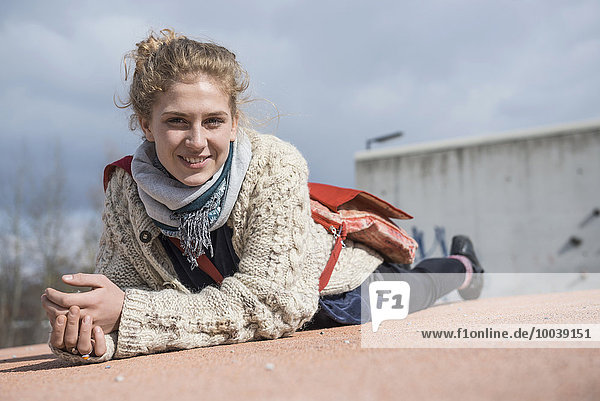 Portrait of a young woman lying on roundabout and smiling  Munich  Bavaria  Germany