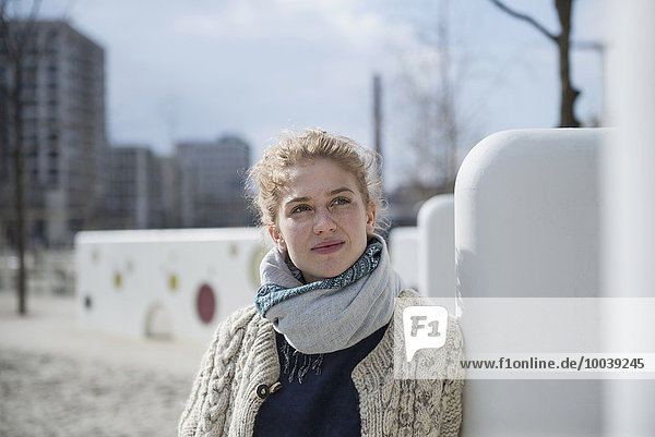 Young woman leaning against wall in playground  Munich  Bavaria  Germany