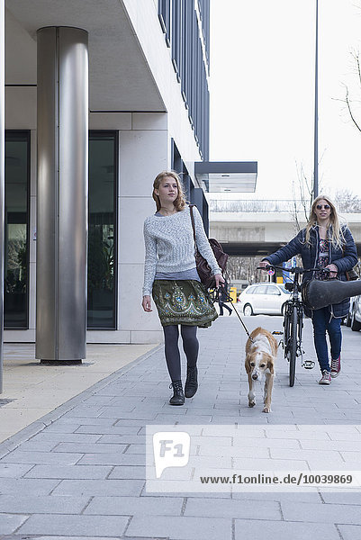 Women walking with her dog beside teenage girl  Munich  Bavaria  Germany