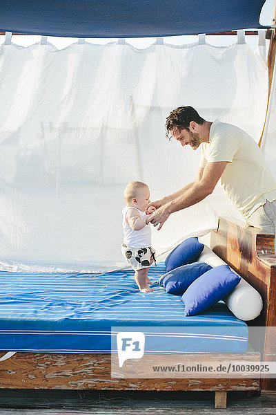 Father with baby playing on outdoor bed