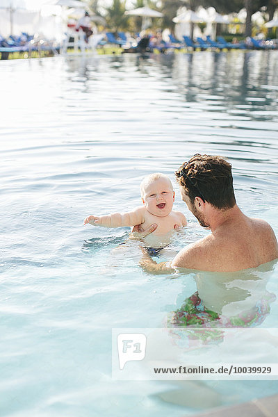 Father playing with baby in swimming-pool