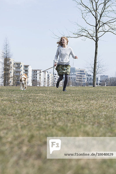 Young woman running in park with dog  Munich  Bavaria  Germany