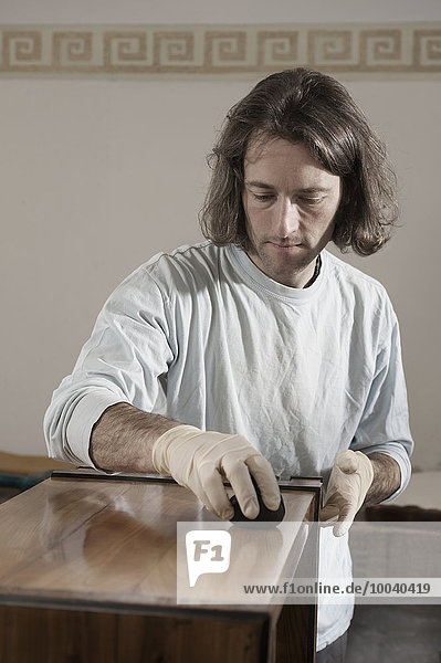 Carpenter French polishing on wooden drawer at workshop  Bavaria  Germany