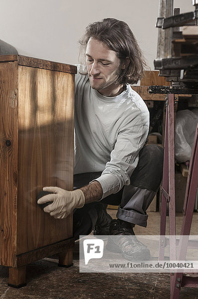 Carpenter French polishing on wooden drawer at workshop  Bavaria  Germany