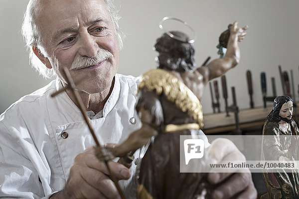 Senior sculptor works on a Jesus Christ statue at workshop  Bavaria  Germany