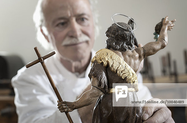 Senior sculptor works on a Jesus Christ statue at workshop  Bavaria  Germany