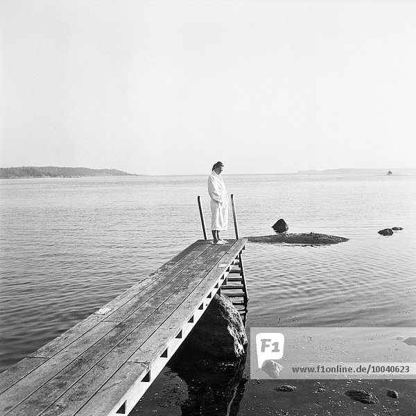Woman in dressing gown standing at jetty