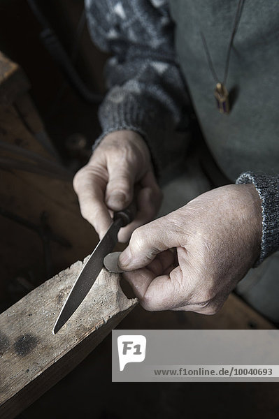 Senior male goldsmith shaping crystal with rasp in workshop  Bavaria  Germany