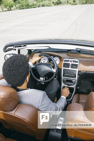 Young black man driving convertible