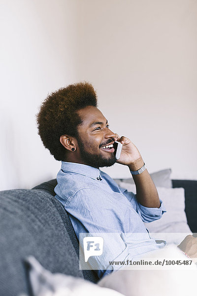 Young Afro American man on the phone  sitting on couch