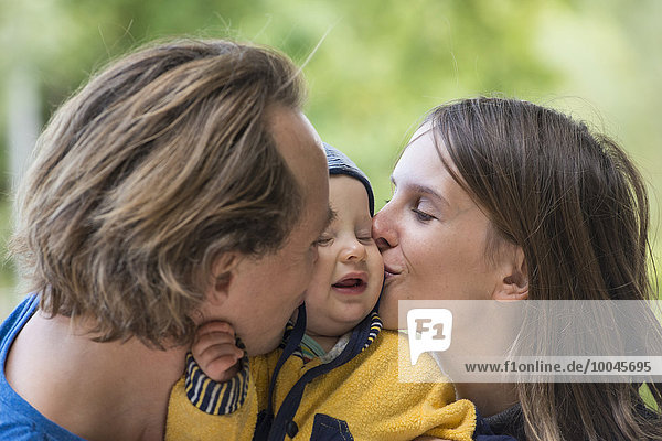 Vater und Mutter küssen ihren kleinen Sohn.