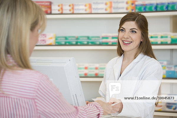 Portrait of smiling female pharmacist taking prescription from customer