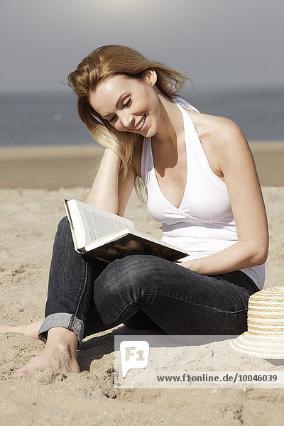 Niederlande  Scheveningen  junge Frau beim Lesen am Strand