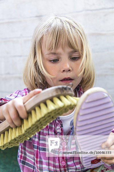 Porträt des kleinen Mädchens beim Schuhputzen