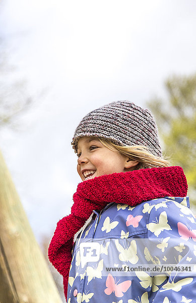 Glückliches kleines Mädchen mit rotem Schal und Wollmütze