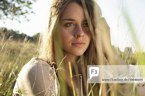 Portrait of daydreaming female teenager sitting on a meadow