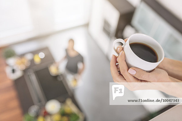 Woman's hand holding cup of black coffee