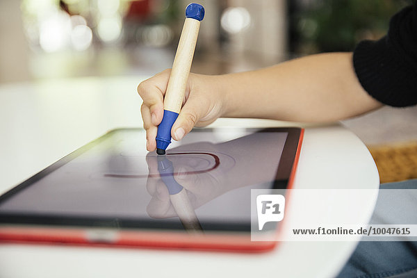 Hand of child drawing letter with a digital pen on digital tablet
