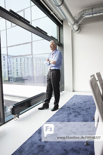 Successful manager standing at window in conference room
