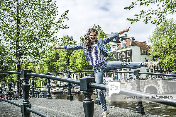 Niederlande  Amsterdam  weibliche Touristen  die auf einem Bein auf einer Fußgängerbrücke balancieren.