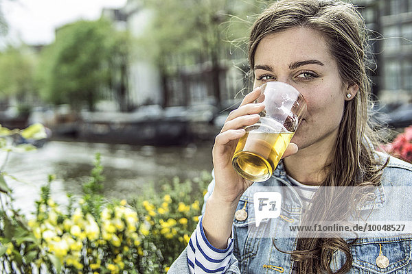 Niederlande  Amsterdam  Frau trinkt Bier in einem Straßencafé