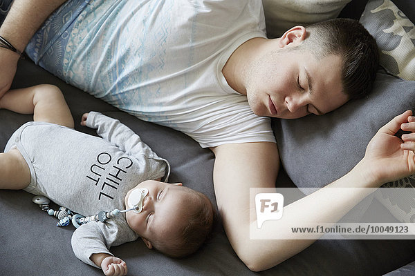 Junger Vater und Baby schlafen auf der Couch