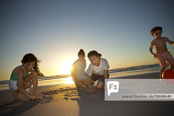 Familie am Strand bei Sonnenuntergang Zeichnen im Sand