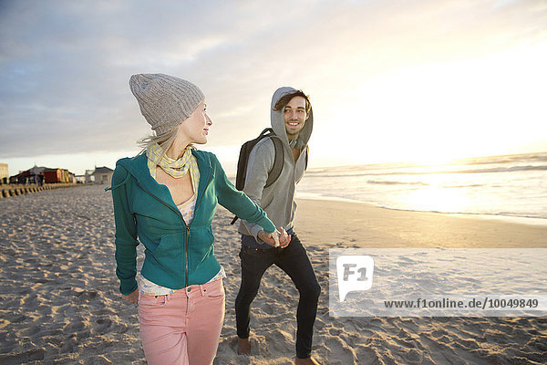 Young couple walking on beach at sunrise