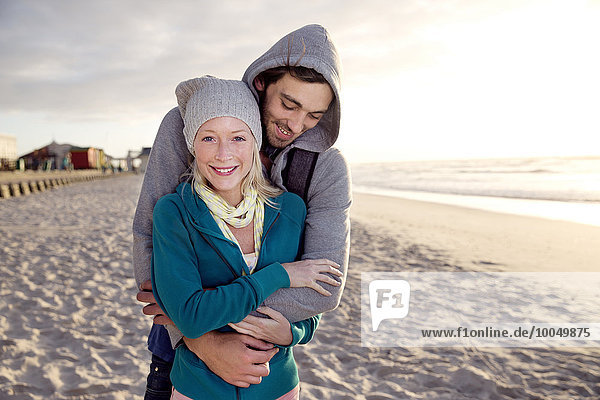 Happy young couple on beach at sunrise