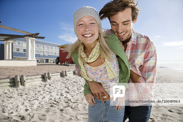 Glückliches junges Paar  das sich am Strand umarmt.