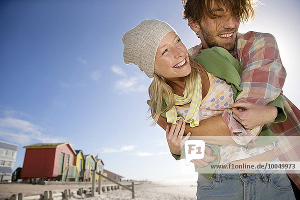 Glückliches junges Paar  das sich am Strand umarmt.