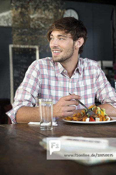 Junger Mann in einem Restaurant beim Mittagessen