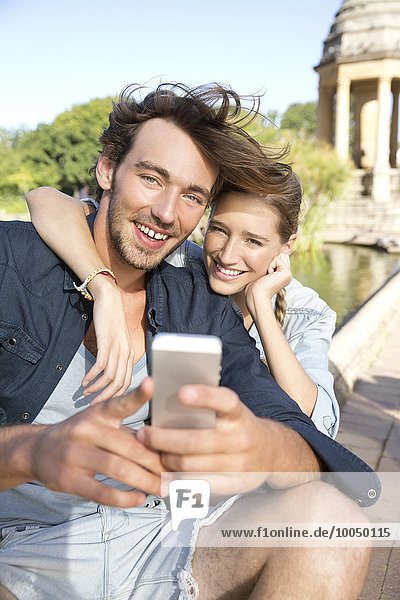 Glückliches junges Paar im Park mit einem Selfie