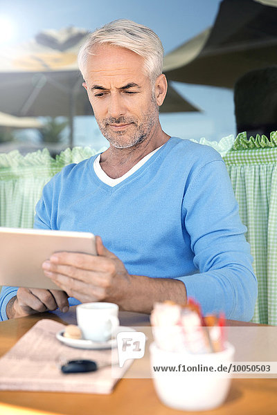 Porträt eines Mannes vor einem Cafe mit digitalem Tablett