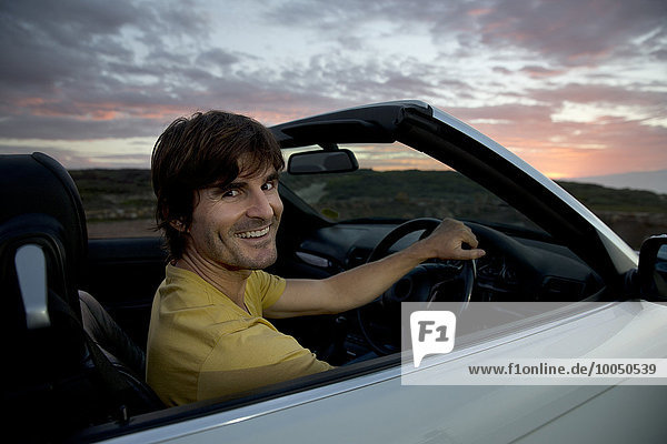 Südafrika  Porträt eines lächelnden Mannes in einem Cabriolet