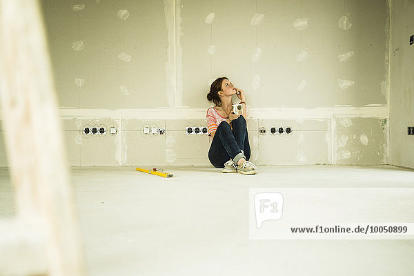 Young woman renovating sitting at blank wall