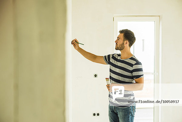 Young man renovating drawing marking at wall