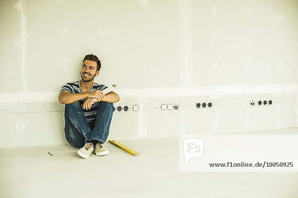 Young man renovating sitting at blank wall