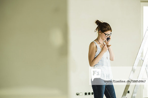Young woman renovating talking on cell phone