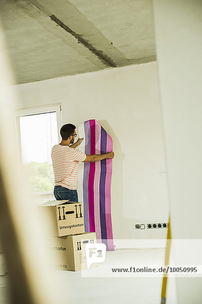 Young man renovating holding wallpaper