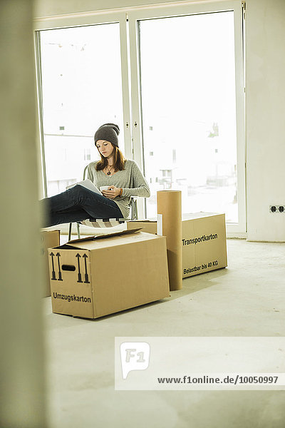 Young woman using laptop surrounded by cardboard boxes