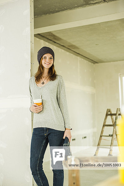 Lächelnde junge Frau bei einer Kaffeepause nach der Renovierung