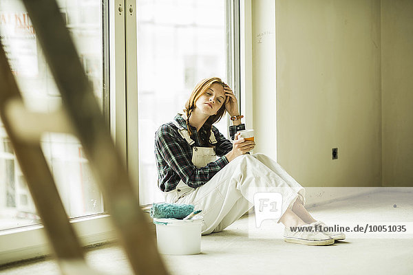 Exhausted young woman having a break from renovating