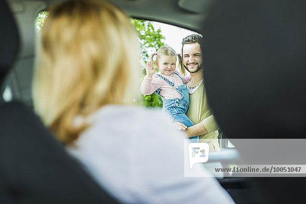 Mädchen mit Vater verabschiedet sich von der Mutter im Auto