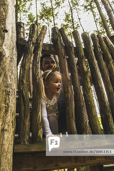 Vater und Mädchen schauen von hinten auf den Holzzaun