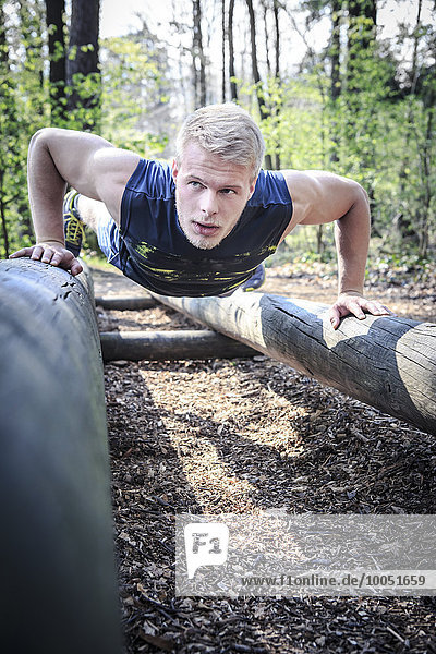 Deutschland,  Coburg,  Junger Mann trainiert Liegestütze auf einem Fitness-Parcours im Wald