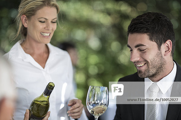 Kellnerin und Kundin mit einem Glas Weißwein